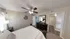 Elegant bedroom with cozy decor, featuring a king-sized bed, sleek dark wood dresser, modern ceiling fan, and a large mirror.