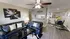 Charming living room with modern art, comfortable seating, ceiling fan, and an open layout leading to a cozy dining area with bright decor.
