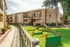 Charming apartment complex with lush green courtyard and children’s play area, featuring modern architecture and sunny outdoor spaces.