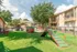 Charming apartment community showcasing a dog-friendly play area with agility equipment surrounded by lush greenery and cozy buildings.