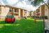 Charming apartment complex with spacious balconies, surrounded by lush greenery and a vibrant pet play area.