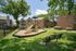 Charming apartment complex featuring a vibrant playground surrounded by lush greenery and modern brick buildings.