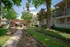 Charming apartment complex with lush landscaping, a shaded pergola, and modern amenities in a serene setting.