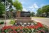 Inviting entrance to City Crossing Apartments surrounded by vibrant flowers and lush greenery on a bright, sunny day.