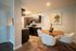 Contemporary dining area featuring a stylish round table with white chairs and vibrant decor, alongside a modern kitchen with dark wood cabinetry.