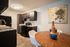 Chic kitchen and dining area featuring modern dark cabinets, elegant wooden decor, and stylish lighting above a cozy round table.