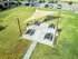 Charming outdoor picnic area with modern shade sail, multiple seating options, and built-in grills, surrounded by lush green space.