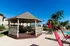 Inviting outdoor space featuring a charming gazebo, lush palm trees, and a sparkling swimming pool with vibrant seating for relaxation.