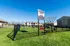 Charming on-site dog park with agility equipment, set against a backdrop of modern apartment buildings under a clear blue sky.