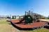 Inviting outdoor playground featuring a modern slide and climbing structure, set against charming apartment homes with sunny blue skies.