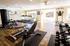 Bright, spacious fitness center featuring modern exercise equipment, treadmills lined up by large windows, and a selection of free weights on pristine wooden floors.