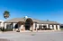 Elegant clubhouse exterior with classic architecture, manicured landscaping, and a welcoming entrance under a clear blue sky.