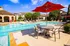Luxurious poolside oasis featuring vibrant red umbrellas, stylish lounge chairs, and serene landscaping for a resort-like living experience.