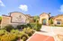 Charming Valencia Place exterior showcasing luxury apartment entrance framed by vibrant landscaping and clear blue sky.