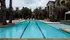 Luxurious apartment complex with a sparkling swimming pool, surrounded by lush palm trees and elegant loungers for a serene retreat.