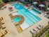 Luxurious outdoor pool area with stylish lounge chairs, vibrant red umbrellas, and a relaxing hot tub, perfect for leisure and recreation.