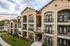 Elegant apartment complex with modern architecture, spacious balconies, and lush green surroundings.