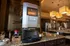 Luxurious kitchen area with modern coffee machine, granite countertops, and elegant pendant lighting in a contemporary apartment setting.