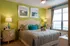 Bright and inviting bedroom with olive-green accent wall, plush bedding, and stylish decor.