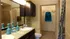 Elegant bathroom with dual sinks, granite countertop, chic blue decor, and a convenient walk-in closet.