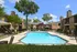 Inviting apartment complex offering a pristine swimming pool, charming brick architecture, and lush greenery for a relaxing lifestyle.