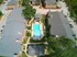 Elegant aerial view of a charming apartment complex featuring a sparkling central pool, surrounded by lush greenery and inviting walkways.