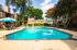 Inviting outdoor swimming pool surrounded by sunlit brick apartments and lush trees, perfect for relaxation and leisure.
