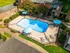 Inviting apartment complex with a beautifully maintained pool area, surrounded by elegant landscaping and leisure seating under umbrellas.