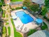 Inviting aerial view of a sparkling apartment pool surrounded by lush greenery and stylish patio seating with umbrellas.