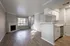 Modern open-concept living area featuring elegant hardwood floors, a cozy fireplace, and a sleek kitchen with white cabinetry and stainless steel appliances.
