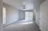 Bright and spacious living room with modern ceiling fan and plush carpeting, featuring large windows and sliding glass doors leading to a sunny outdoor space.