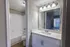 Bright and inviting bathroom with modern fixtures, elegant vanity, and a spacious mirror in a cozy apartment setting.