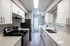 Modern galley kitchen with sleek white cabinetry, stainless steel appliances, and in-unit laundry for convenient urban living.