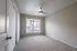 Bright and spacious empty room with plush carpeting, large window with blinds, and modern ceiling fan, perfect for personalization.