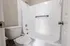 Modern bathroom with sleek design featuring a pristine bathtub, elegant fixtures, and a white tiled wall.
