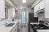 Contemporary kitchen and laundry room featuring sleek white cabinets, modern appliances, and elegant countertops with natural light streaming in.