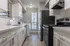 Modern kitchen with sleek white cabinetry, stainless steel appliances, and convenient in-unit laundry. Natural light accentuates the stylish design.