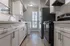 Modern kitchen with sleek white cabinetry, stainless steel appliances, and hardwood flooring, bathed in natural light.