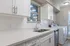 Modern kitchen and laundry room with sleek white cabinetry, a streamlined countertop, and integrated appliances for effortless living.