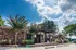 Charming apartment entrance with a beautifully landscaped garden and vibrant flowers under a bright blue sky.