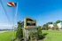Welcoming Deerbrook Forest Apartments entrance sign surrounded by lush greenery and vibrant flags under a clear blue sky.