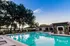 Inviting outdoor pool with elegant lounge chairs and lush trees, perfect for relaxing under a clear blue sky.