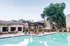 Inviting apartment complex pool area featuring a modern pergola, lush greenery, and relaxing lounging space.