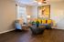 Charming living room with stylish gray sofas, vibrant yellow cushions, modern round coffee table, and elegant wall art, perfect for relaxation.