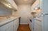 Charming galley-style kitchen with modern appliances, classic white cabinetry, and sleek countertops, offering a cozy yet efficient cooking space.