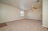 Inviting living room with plush carpet, soft neutral walls, and ceiling fan creating a comfortable and welcoming ambiance.