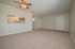 Inviting living room with plush carpet, ceiling fan, and open kitchen bar for modern entertaining.
