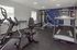 Modern apartment gym with state-of-the-art equipment including treadmill, exercise bike, and weight machine, all in a well-lit, spacious room.