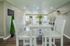 Bright and welcoming dining area featuring modern white furniture, lush greenery, and sleek wood flooring.