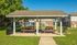 Inviting outdoor picnic area with shelter and rustic wooden tables, surrounded by lush green lawns in a charming apartment community.